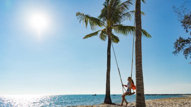 Tatil konsepti. Genç kadın bir plaj salıncak üzerinde salıncak. Phu Quoc plajda mutlu gezgin kadınlar