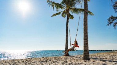 Tatil konsepti. Genç kadın bir plaj salıncak üzerinde salıncak. Phu Quoc plajda mutlu gezgin kadınlar