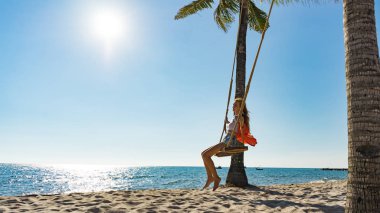 Tatil konsepti. Genç kadın bir plaj salıncak üzerinde salıncak. Phu Quoc plajda mutlu gezgin kadınlar