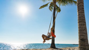 Tatil konsepti. Genç kadın bir plaj salıncak üzerinde salıncak. Phu Quoc plajda mutlu gezgin kadınlar