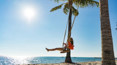 Tatil konsepti. Genç kadın bir plaj salıncak üzerinde salıncak. Phu Quoc plajda mutlu gezgin kadınlar