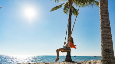 Tatil konsepti. Genç kadın bir plaj salıncak üzerinde salıncak. Phu Quoc plajda mutlu gezgin kadınlar