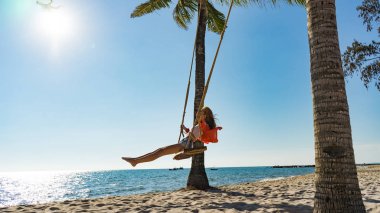 Tatil konsepti. Genç kadın bir plaj salıncak üzerinde salıncak. Phu Quoc plajda mutlu gezgin kadınlar