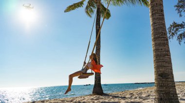 Tatil konsepti. Genç kadın bir plaj salıncak üzerinde salıncak. Phu Quoc plajda mutlu gezgin kadınlar
