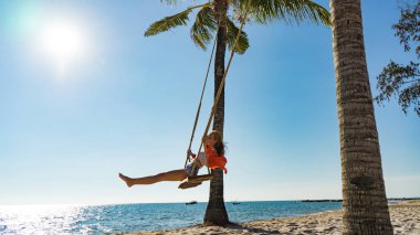 Tatil konsepti. Genç kadın bir plaj salıncak üzerinde salıncak. Phu Quoc plajda mutlu gezgin kadınlar