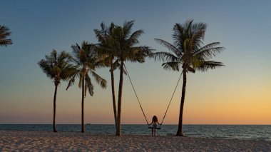Tatil konsepti. Genç kadın bir plaj salıncak üzerinde salıncak. Phu Quoc plajda mutlu gezgin kadınlar