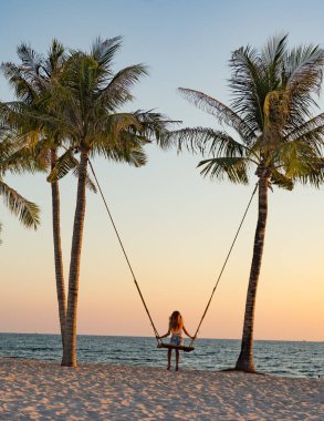 Tatil konsepti. Genç kadın bir plaj salıncak üzerinde salıncak. Phu Quoc plajda mutlu gezgin kadınlar