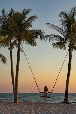 Tatil konsepti. Genç kadın bir plaj salıncak üzerinde salıncak. Phu Quoc plajda mutlu gezgin kadınlar