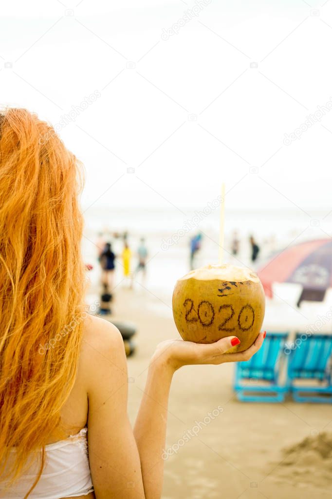 Coconut with the inscription twenty twenty, 2020, on the beach by the sea.