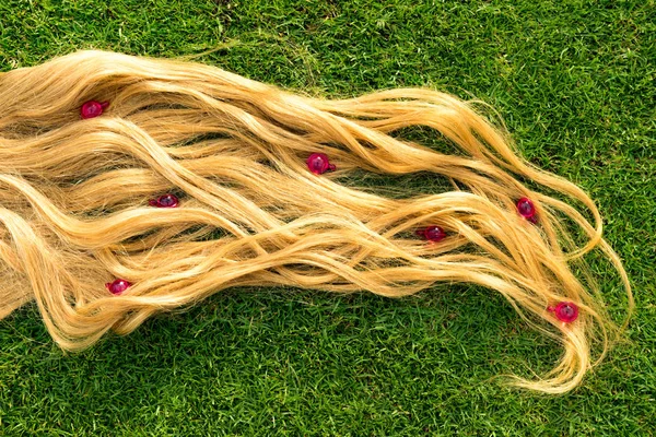 Blond hair nourishment. pink vitamin serum capsule on grass background.Light Hair loss treatment