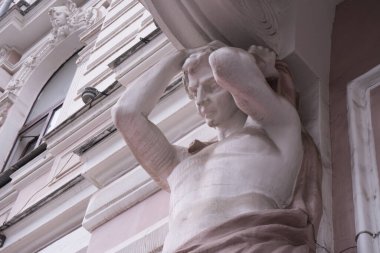 Anchient güçlü vücut adamının heykeliyle dekore edilmiş bina mermer süslemeli Yunan Tanrısı heykeli tarihi bina cephesinde. Güzel antik mimari kavramı.