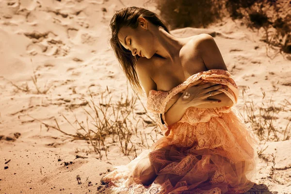年轻的感性女士 闭上眼睛坐在一个美丽的粉红色礼服的沙漠 — 图库照片