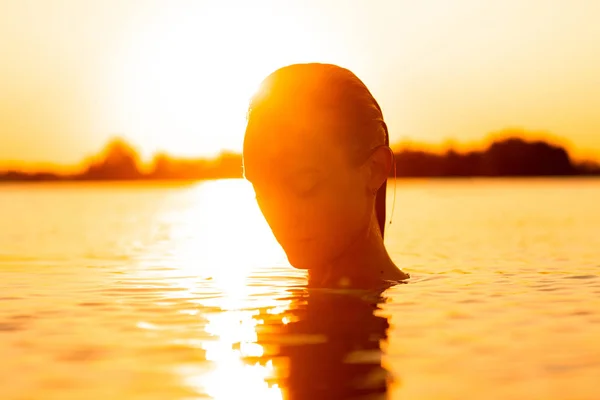 young sexual lady in the sea at warm sunset