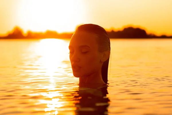 young sexual lady in the sea at warm sunset