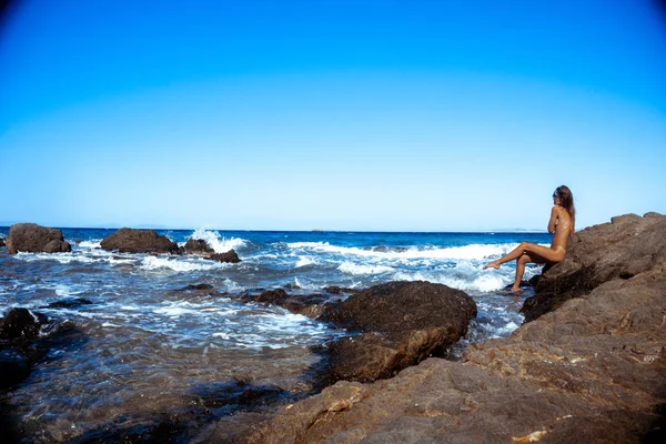 Schöne nackte Mädchen auf einer felsigen Küste — Stockfoto
