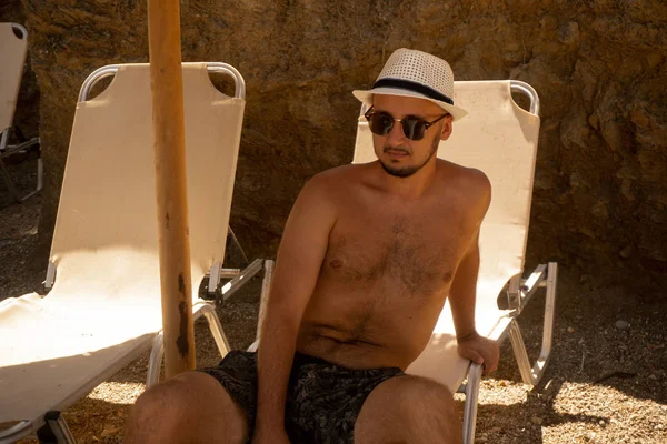 帽子と眼鏡を身に着けている若い男がビーチで日焼け — ストック写真