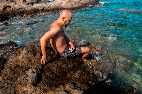 Jeune Homme Chauve Assis Sur Plage Rocheuse — Photo