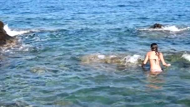 Schöne junge Frau am felsigen Strand — Stockvideo