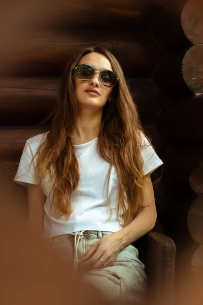 Sexy dame in zonnebril op het houten huis poseren — Stockfoto