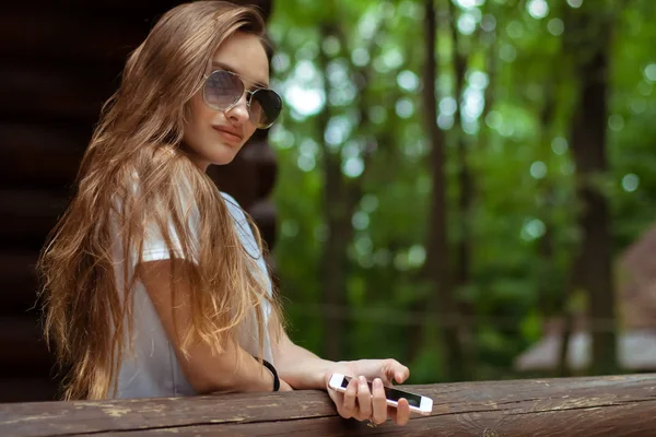 Sexy dame en lunettes de soleil à la maison en bois posant — Photo