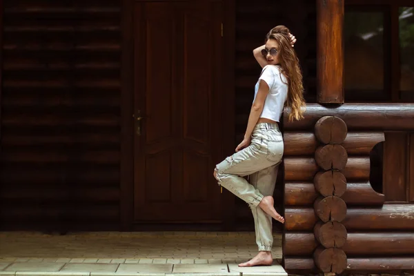 Seksowna dama w okulary przeciwsłoneczne w drewnianym domu stwarzające — Zdjęcie stockowe