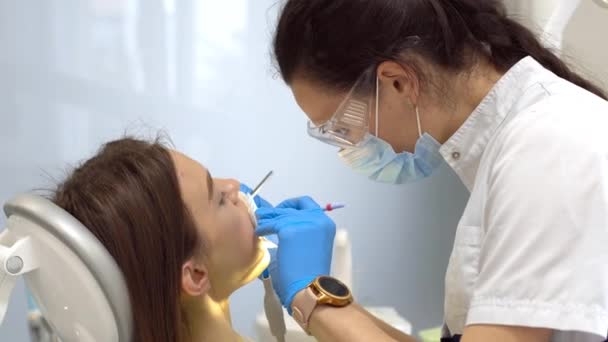 In the clinic dentist treats the patient teeth — Stock Video