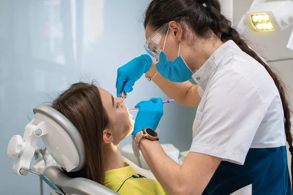 Οδοντίατρος αντιμετωπίζει τα δόντια σε ένα κορίτσι σε μια κλινική — Φωτογραφία Αρχείου