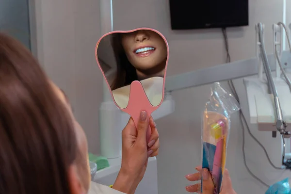 Dívka obdivuje nový úsměv v zrcadle na zubní klinice — Stock fotografie