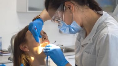 Dişçi klinikte kızların dişlerini tedavi ediyor.