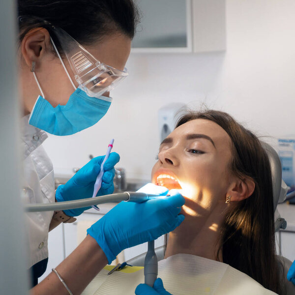 square photo of dentist treat the teeth of a beautiful patient