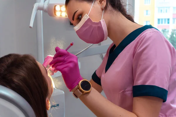 Fogorvos rózsaszín egyenruhában kezeli a fogak a beteg — Stock Fotó