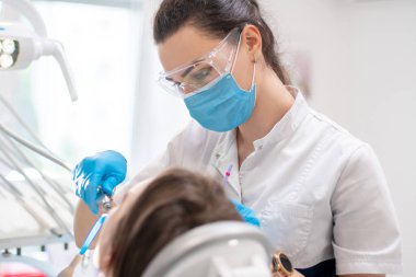 Diş hekiminin portresi klinikte dişlerini tedavi ediyor.