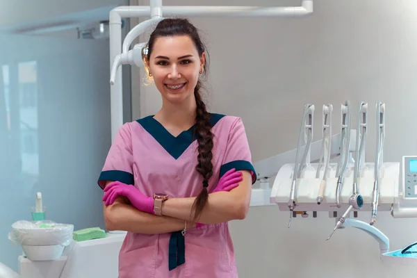 Pembe Üniformalı Güzel Dişçi Klinikteki Kamerada Gülümsüyor — Stok fotoğraf