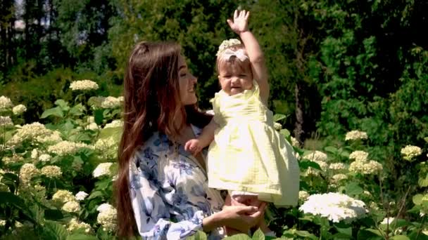 Mignon jeune mère avec liitle bébé fille en fleurs