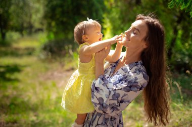 Tatlı genç anne bahçede küçük kızıyla eğleniyor.