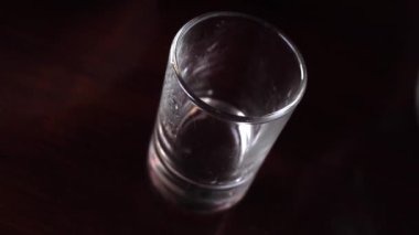Bir sürahi dolusu votkaya votka dökülüyor. Bardakta alkolsüz içki.