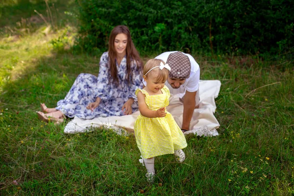 Vrolijk klein meisje rent uit haar ouders op de picknick tijd in de tuin — Stockfoto