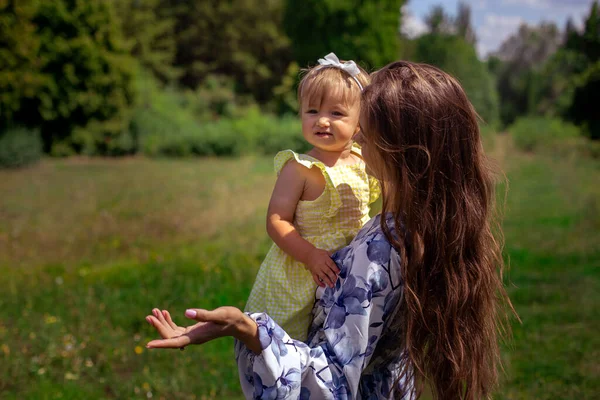 母とともに彼女の美しいです赤ちゃん女の子上の彼女の手話とポイント脇にザ緑の公園 — ストック写真