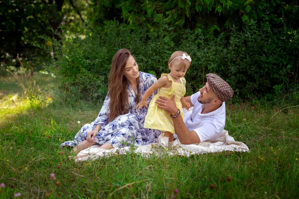 Feliz familia joven juega con su hija bebé liitle en el prado verde — Foto de Stock