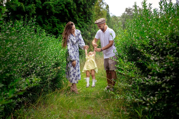 Padres felices jugando con su pequeña niña en el jardín verde — Foto de Stock