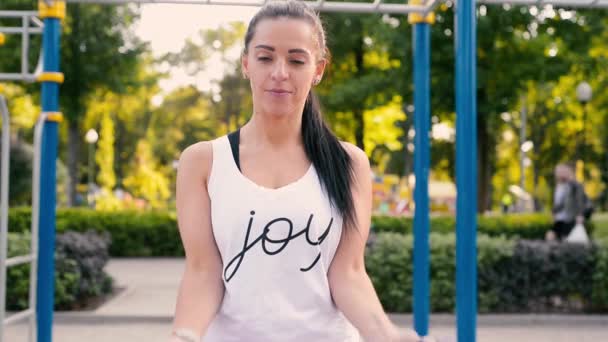 Brünette Frau trainiert an warmen Sommertagen im Park ihre Bizeps-Muskeln mit Kurzhanteln — Stockvideo