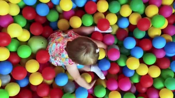 Alegre niña juega con bolas multicolor en la piscina de los niños — Vídeo de stock