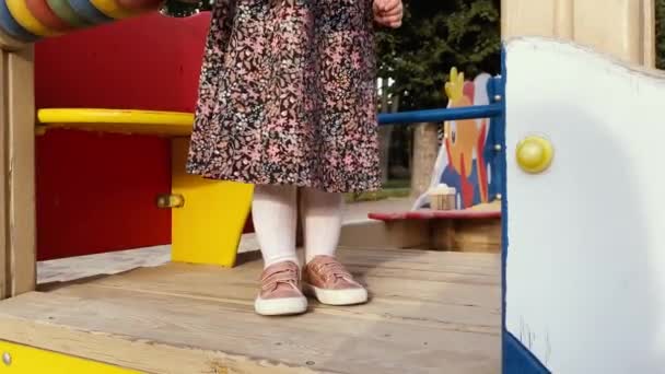 Primer plano de las pequeñas piernas de bebé en un parque infantil — Vídeo de stock