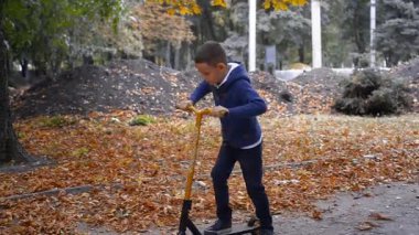Genç bir çocuk sonbahar günü motosiklete biner.