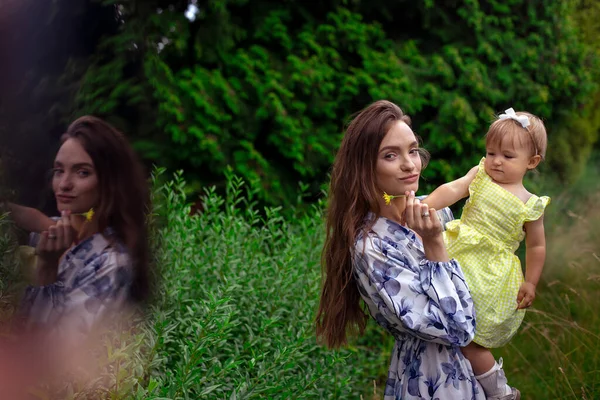Moeder dragen haar dochtertje in de groene tuin — Stockfoto
