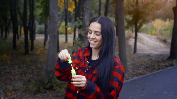 Gai brunette femme souffler des bulles au parc à chaud jour d'automne — Video