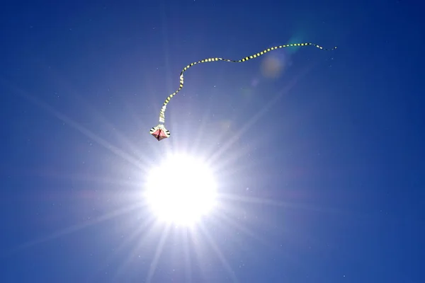 在蓝天和太阳的映衬下 用条纹长尾放风筝 放风筝节 — 图库照片