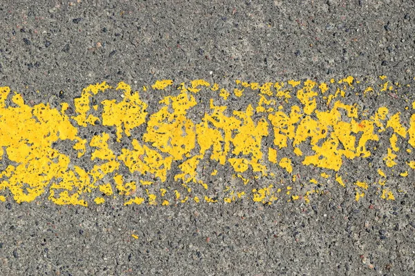 peeling yellow strip painted with road paint on asphalt