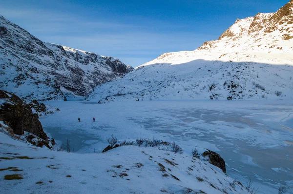 Lofoten Adaları'nda donmuş bir gölün üzerinde yürüyen iki yürüyüşçü