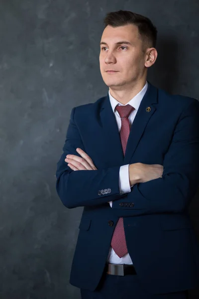 Portrait of young intelligent man lawyer standing with crossed arms in modern office building interior, successful male bank employee dressed in luxury suit posing with copy space area for your text